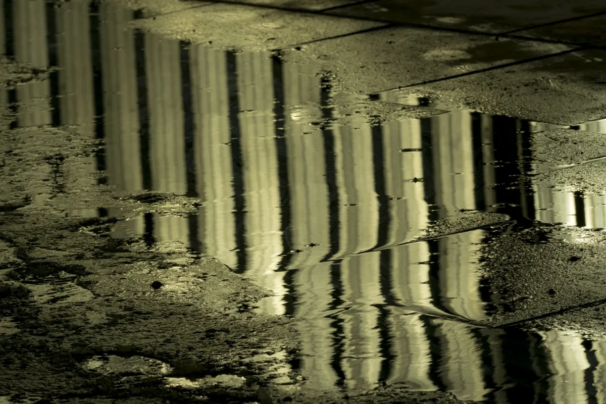 Distorted vertical reflections stretching across a rain puddle